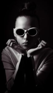 Woman with sunglasses and hair bun in dark background