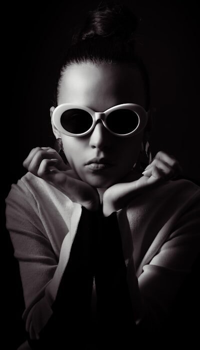 Woman with sunglasses and hair bun in dark background