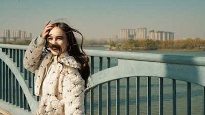 Young woman on a bridge with city buildings in background