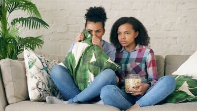 Two people watching tv, one holding popcorn.