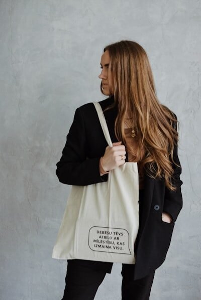 a woman is holding a white bag with writing on it