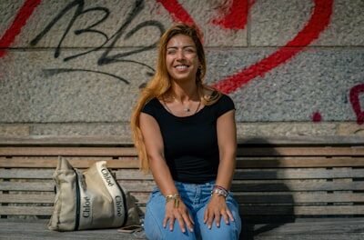 Smiling woman sits on a bench with graffiti.