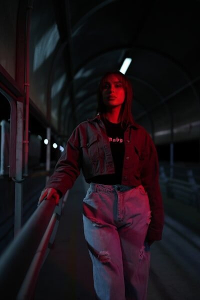 Woman standing in dimly lit tunnel with red light