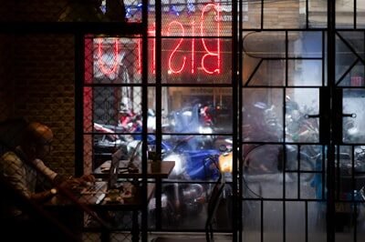 a man sitting at a table in front of a neon sign