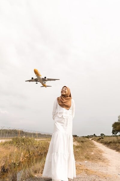 Woman in hijab watches airplane approach