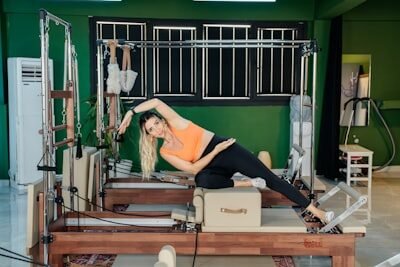 Woman does pilates exercises on a reformer machine.