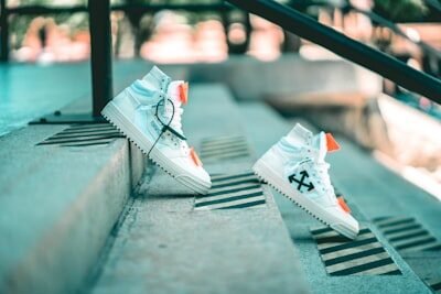 a pair of white sneakers sitting on top of a cement step