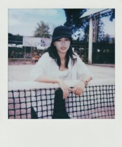 Young woman wearing a baseball cap and white shirt.